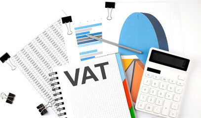 Text VAT on a notebook on diagram and charts with calculator and pen