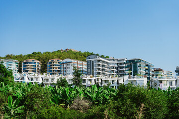 Fototapeta premium Sandy path leading to a new real estate building with sky in background and green trees in line
