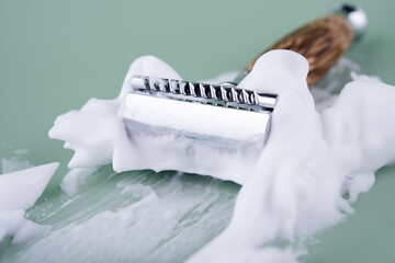 Close up of razor and foam on a meant background.