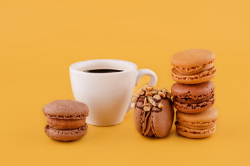 cup of coffee and chocolate macaroons on   yellow background