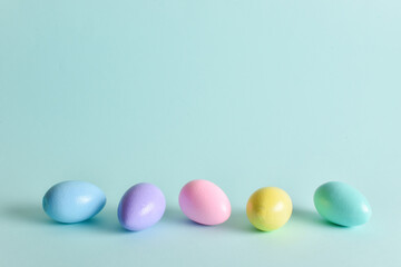 Painted eggs of delicate tones lie on a pale blue background.