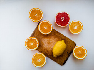 Sliced oranges, grapefruit and lemon on a cutting board. White background flat lay still life