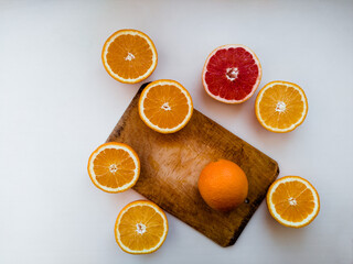 Sliced oranges and grapefruit on a cutting board. White background flat lay still life