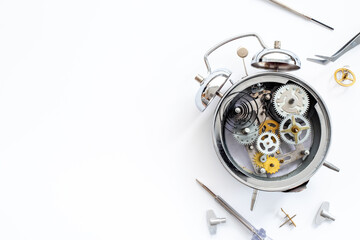 Watchmaker tools near watch mechanism of alarm clock