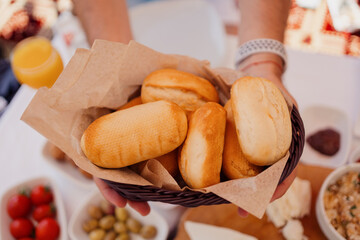 Male hands holding a basket with fresh bread to be served on table. Beautiful food