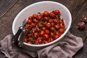 Roasted cherry tomatoes with garlic herbs in baking dish. Healthy food. Top view. Food background.