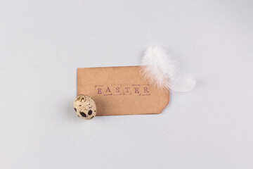 Easter minimal concept. Quail eggs with paper tag as easter symbol. Light grey marble background. Place for your text, copy space.