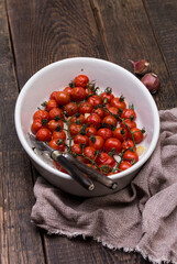 Roasted cherry tomatoes with garlic herbs in baking dish. Healthy food. Top view. Food background.
