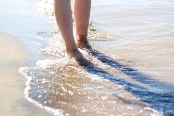 Girl's feet on the beach. Sea waves and legs