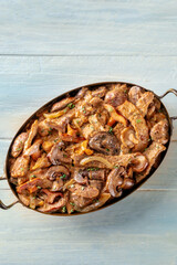 Beef stroganoff, mushroom and meat ragout with cream sauce, traditional Russian dish, in a skillet, overhead shot on a rustic wooden background