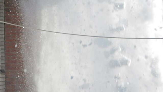Falling snow. A large amount of snow falls from the roof of the house down. Slow motion. Siberia.