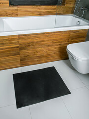 A rubber mat on the floor next to the bathtub in the bathroom. Interior design, modern bath - 488566263