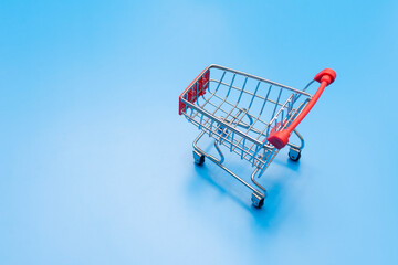empty metal shopping trolley on blue background