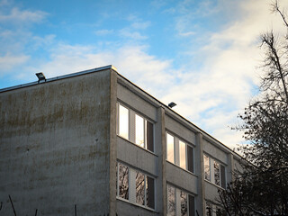 Old white brick wall building corner with squared windows on sky background