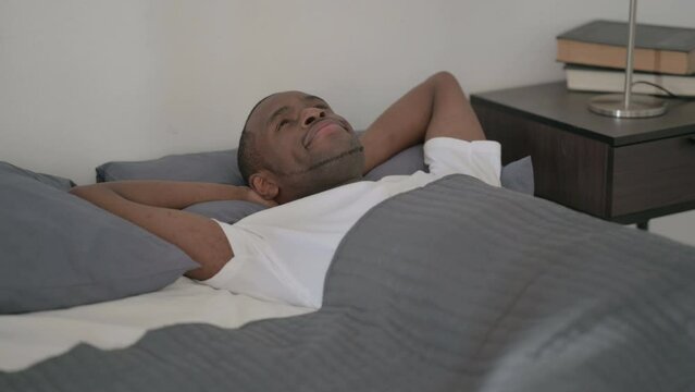 African Man Laying in Bed Awake Thinking 