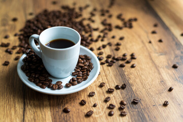 Czarna kawa na drewnianym blacie i rozsypane ziarna.
