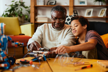 A grandson and granddad interested in robotics making a robot at home for educational purpose.