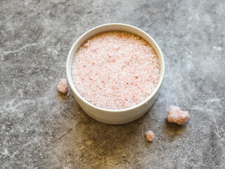 Himalayan pink salt in a bowl against  gray background