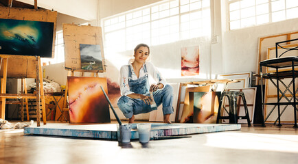 Creative painter squatting close to her painting - obrazy, fototapety, plakaty