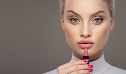 Close-up portrait of a girl. Holds lipstick near her lips.