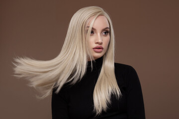 Portrait of a beautiful girl with long airy hair. Brown background.