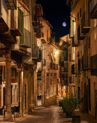 Full moon in medieval porticoed street in Morella, golden light