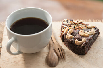 Black coffee and a brownie cake on a wooden table, Placed on a wooden table.