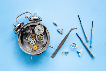 Watchmaker tools near watch mechanism of alarm clock