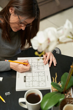 Woman playing sudoku game at home in a game book , alone