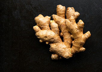 Fresh organic ginger root on dark texture background. Top view, space for text. Anti-inflammatory...
