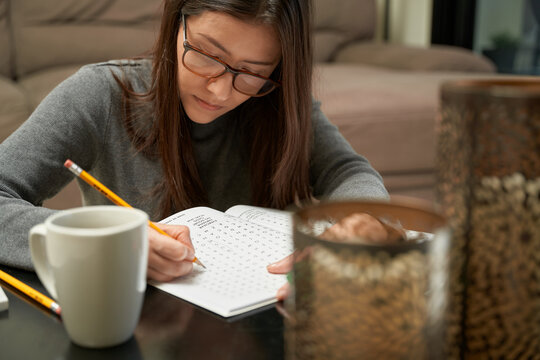 Woman playing Word Find game at home in a game book, alone