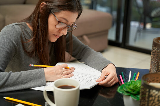Woman playing Word Find game at home in a game book, alone