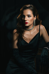 Portrait of brunette woman in classic retro style. Beautiful girl with a hairstyle and makeup with jewelry in vintage retro noir look. Concept of actress from a Hollywood film