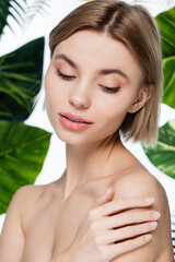 sensual young woman with perfect skin near green palm leaves on white