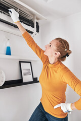 Woman cleaning aircon filters indoor unit at home.