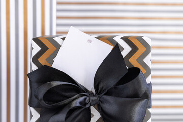 Wrapped present with blank square gift tag and black bow close up, label Mockup