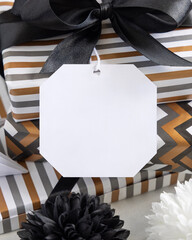 Wrapped present with blank gift tag and black bow close up, label Mockup