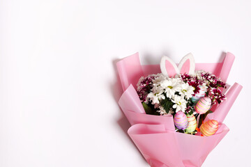 Easter bouquet of flowers and colorful eggs on white background. Copy space