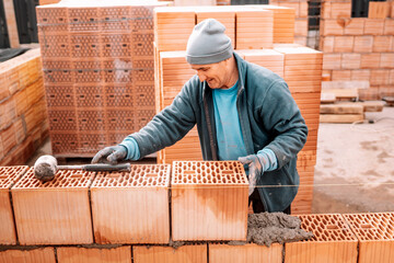 industrial details - Construction bricklayer worker building walls with bricks, mortar and putty knife