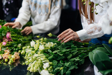 Close-up of women's hands collecting and making beautiful festive bouquets in a cozy flower shop. Floristry and bouquet making in a flower shop. Small business.