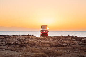 Van Life mit Camper am Strand bei Sonnenaufgang /  Sonnenuntergang im Gegenlicht der Sonne
