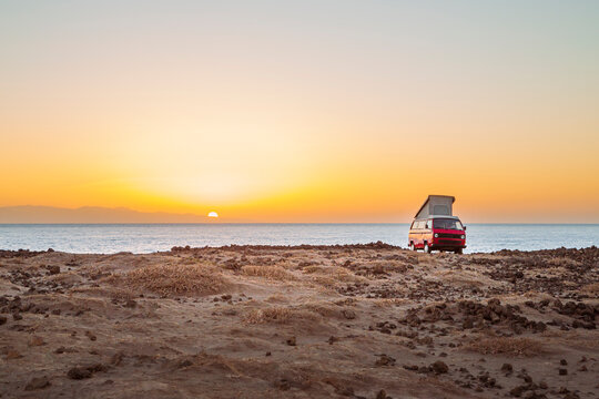 gem&uuml;tliches Van Life mit Camper an K&uuml;ste im Sommer bei Sonnenaufgang /  Sonnenuntergang im Gegenlicht der Sonne