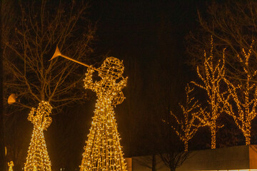 Angel with a lantern made of garlands of lights in a city park