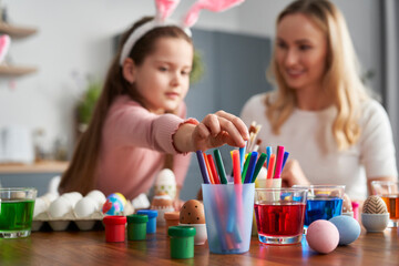 Caucasian mother and daughter decorate easter eggs at home