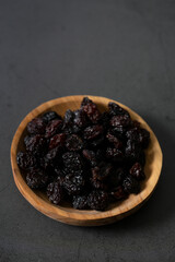 raisins in a wooden bowl on black stone surface