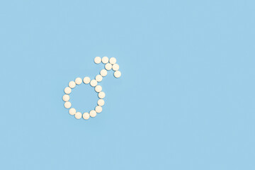 Signo masculino hecho con pastillas pildoras sobre un fondo celeste liso y aislado. Vista superior...