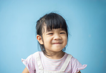 A headshot portrait of a cheerful baby Asian woman, a cute toddler little girl with adorable bangs hair, a child wearing a purple sweater smiling and don't looking to the camera.