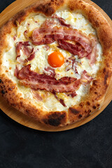 Carbonara pizza with bacon and egg on dark stone background