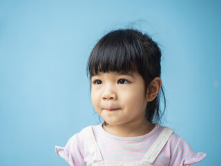 A headshot portrait of a cheerful baby Asian woman, a cute toddler little girl with adorable bangs hair, a child wearing a purple sweater smiling and don't looking to the camera.