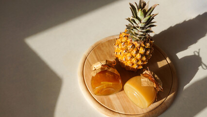 Pineapple jam in glass jar and fresh pineapple fruit with hard shadows